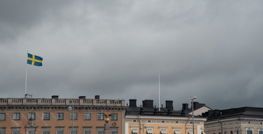 Swedish flag flying over buildings in helsinki finland on a cloudy day