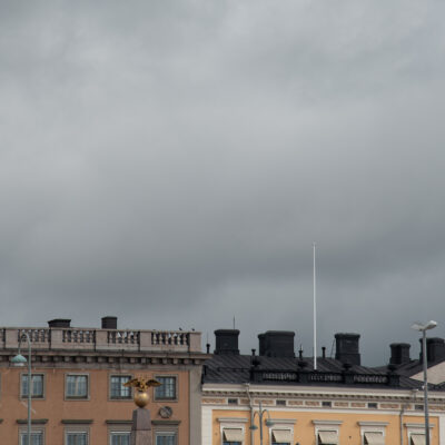 Swedish flag flying over buildings in helsinki finland on a cloudy day
