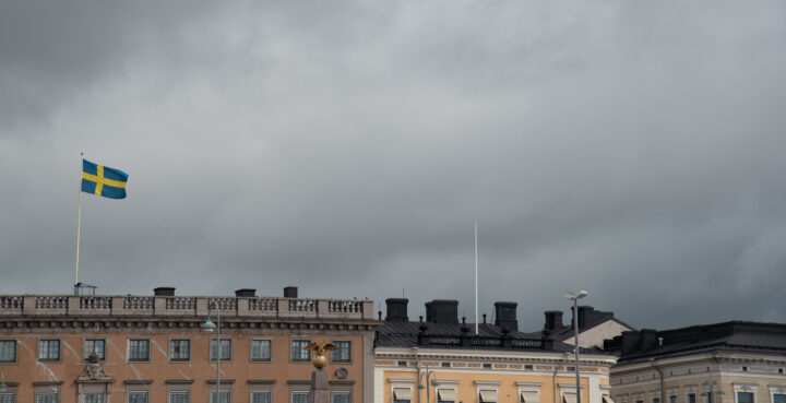 Swedish flag flying over buildings in helsinki finland on a cloudy day